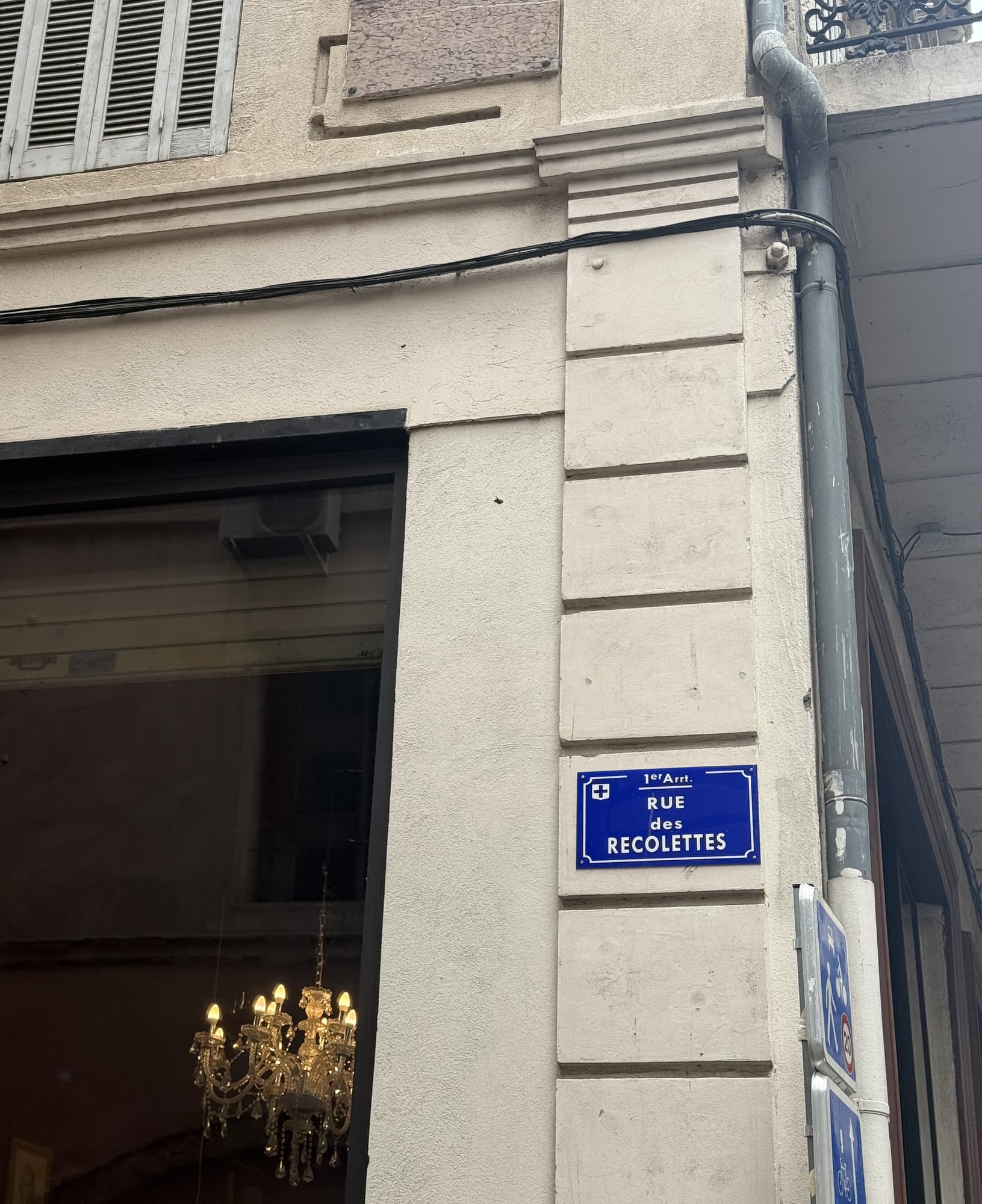 Le panneau émaillé « Rue des Récolettes » sur une façade de pierre, une fenêtre éclairée à gauche